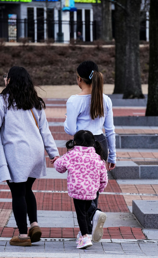 a woman and two children walking down a sidewalk